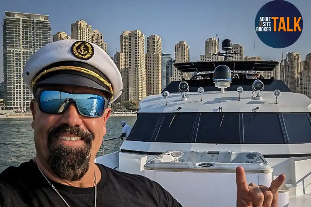 Andy Wullmer mit Kapitänsmütze vor einer Yacht – Adult Site Broker Talk 2025