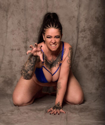 Mara LeNoir in kniender Pose – Camgirl mit wildem Blick und Krallen-Geste