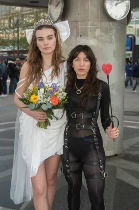 Zwei Frauen in kontrastierenden Outfits mit Blumenstrauß am Alexanderplatz
