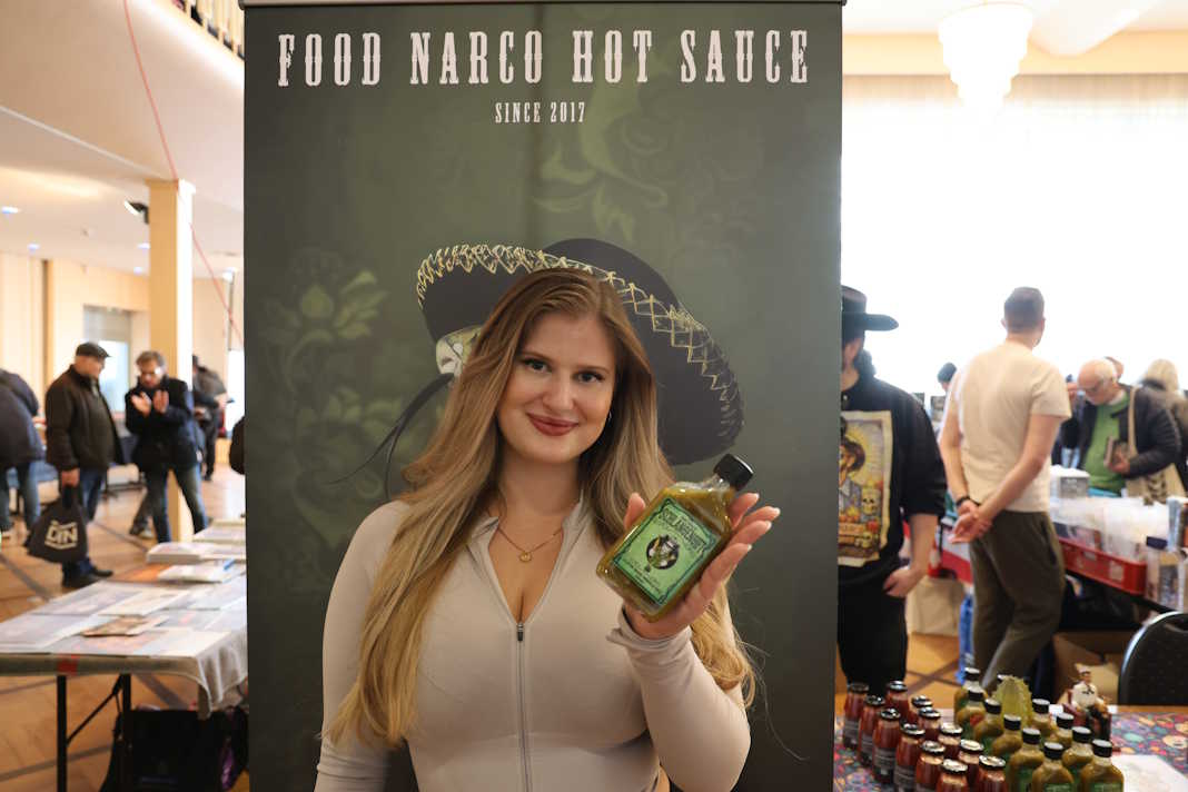 Ellie Blessom hält die Schlangengift-Sauce vor dem Food Narco Banner, Berlin 2026
