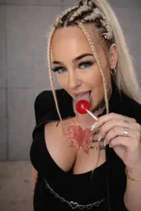Sweet Lilith: Agenturvertrag und Managementdeal in einem Zug Sweet Lilith mit rotem Lollipop, blonden Braids und sichtbaren Tattoos – Portrait aus ihrem Content-Portfolio 2026