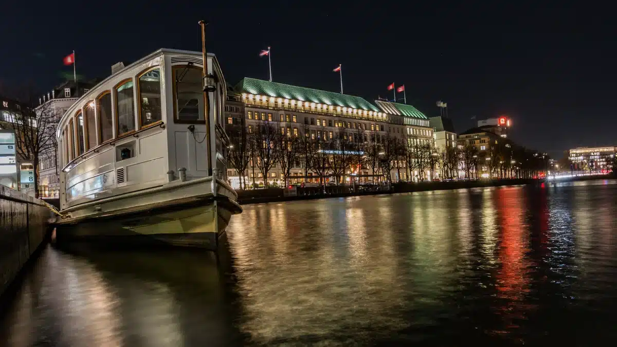 Alsterdampfer am Jungfernstieg bei Nacht, dahinter das beleuchtete Hotel Vier Jahreszeiten an der Binnenalster