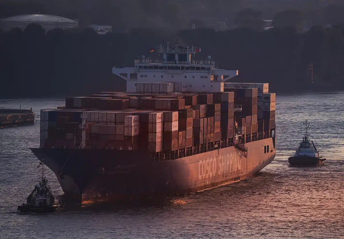 Containerschiff mit zwei Schleppern auf der Elbe bei Hamburg im Abendlicht