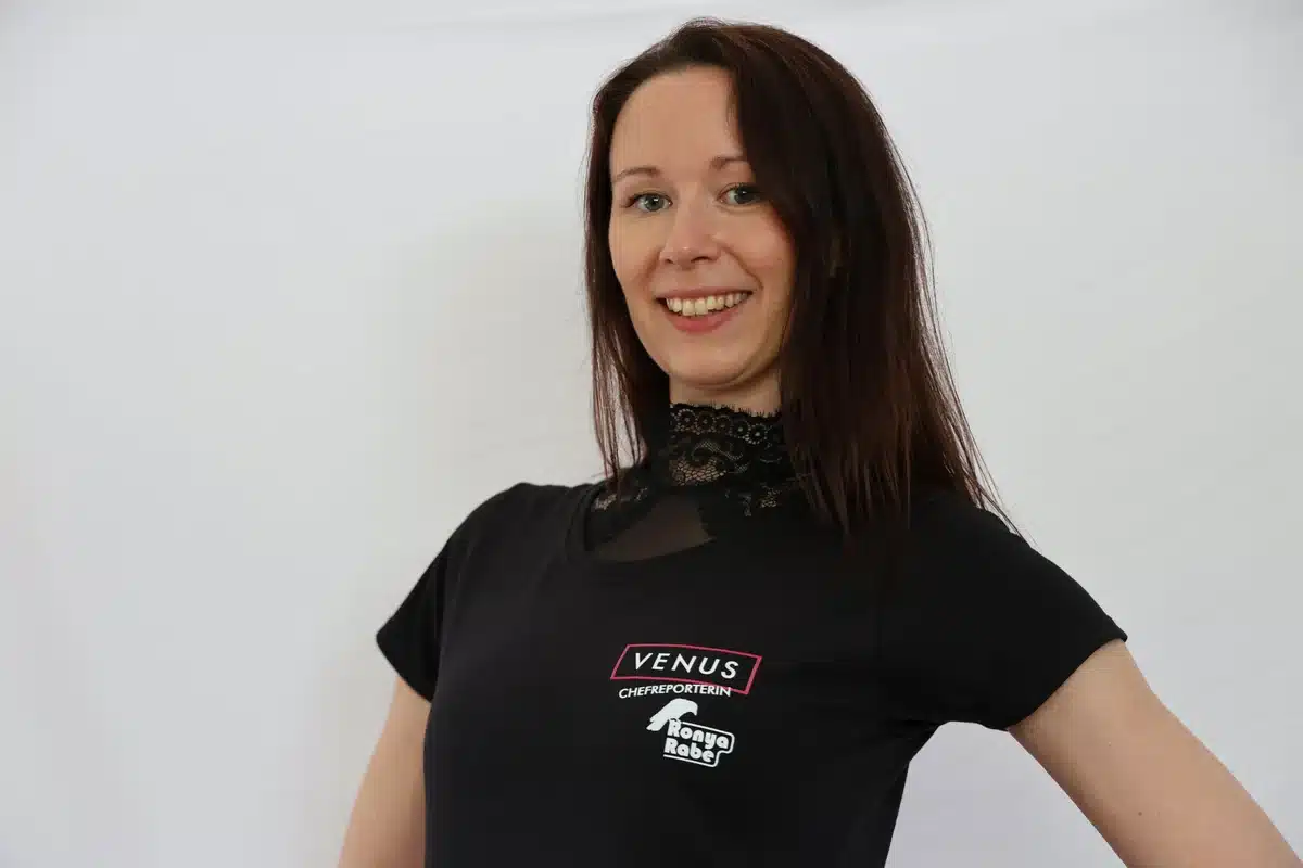 Ronya Rabe lächelnd im schwarzen T-Shirt mit VENUS-Chefreporterin-Logo vor weißem Hintergrund